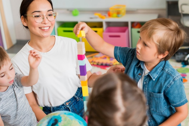 Mujer enseñando a los niños a jugar con torre colorida