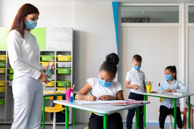 Mujer enseñando a los niños a prevenir una pandemia en clase
