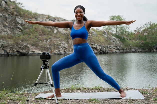 Foto gratuita mujer enseñando una pose de yoga fuera