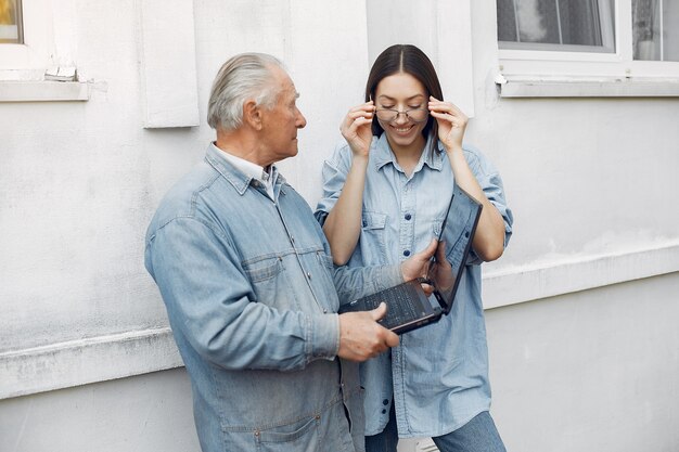 Mujer enseñando a su abuelo a usar una computadora portátil