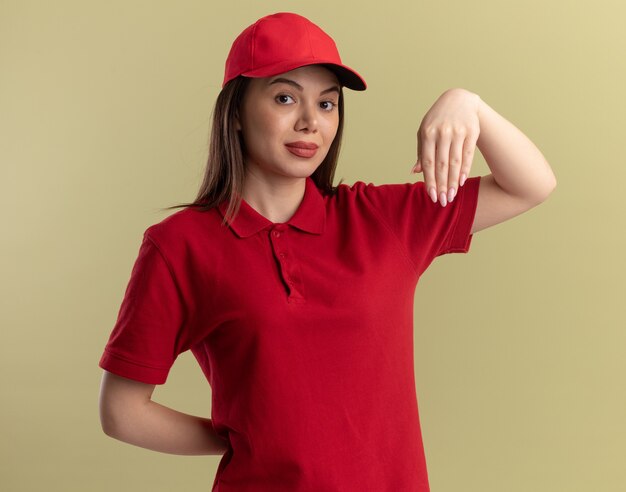 Mujer de entrega bonita confiada en uniforme tiene la mano boca abajo en verde oliva