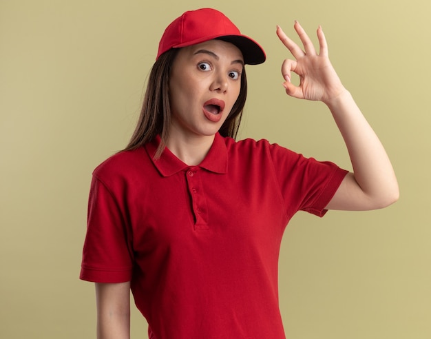 Mujer de entrega bonita emocionada en gestos uniformes signo de mano ok