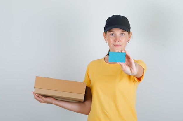 Mujer de entrega con caja de cartón y tarjeta azul en camiseta y gorra