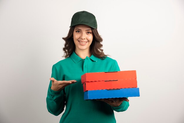 Mujer de entrega con cajas de pizza de pie en blanco.