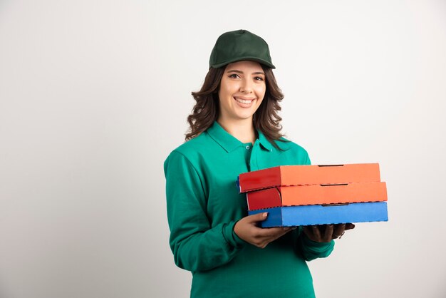 Mujer de entrega con cajas de pizza posando en blanco.