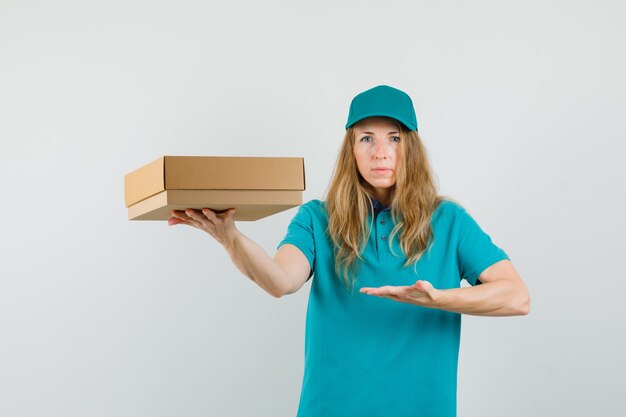 Mujer de entrega en camiseta, gorra mostrando caja de cartón