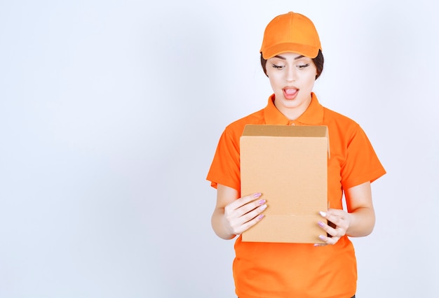 La mujer de entrega conmocionada mirando dentro del paquete