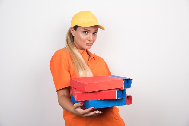 Mujer de entrega mirando al frente y sosteniendo cajas de pizza en un espacio en blanco