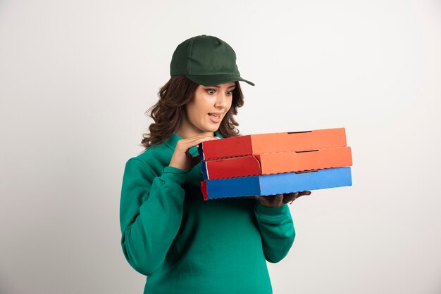 Mujer de entrega mirando cajas de pizza con expresión de sorpresa.