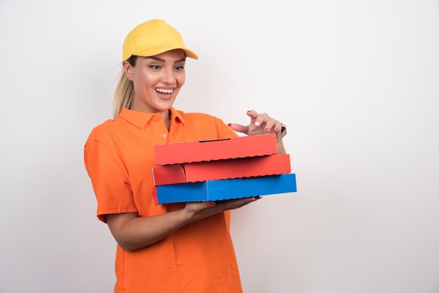 Mujer de entrega de pizza tratando de abrir la caja de pizza con cara feliz en el espacio en blanco