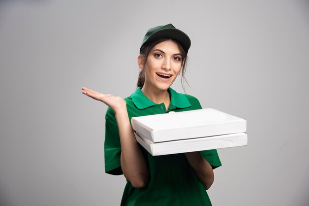 Mujer de entrega posando con cajas de pizza.