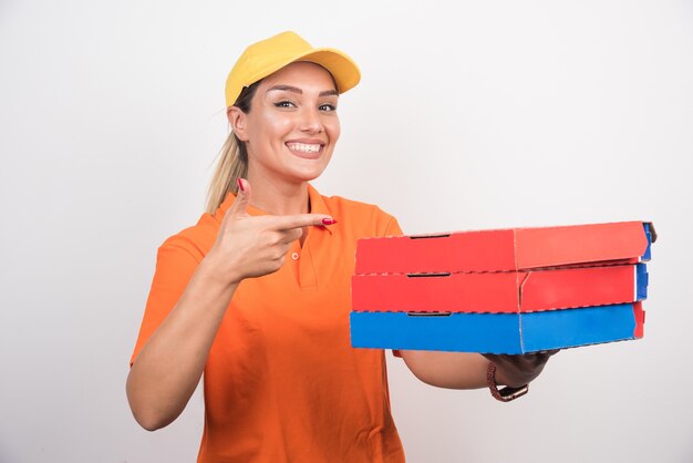 Mujer de entrega rubia sosteniendo pizza apuntando a ellos.