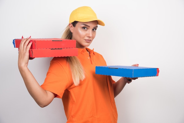 Foto gratuita mujer de entrega con sombrero amarillo sosteniendo cajas de pizza en el espacio en blanco