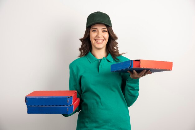 Mujer de entrega sonriendo mientras sostiene la pizza.