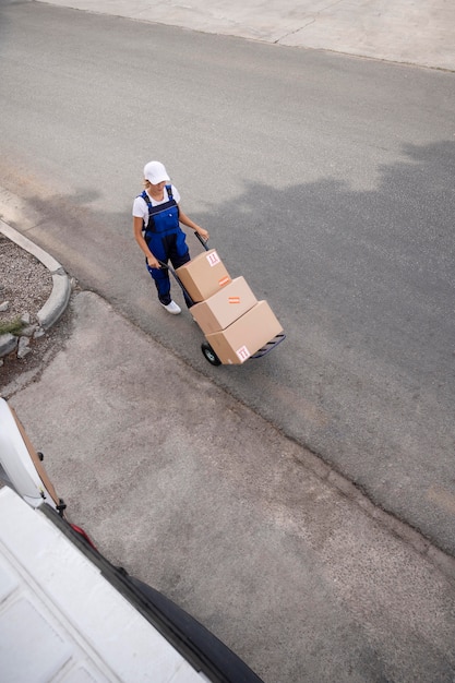 Mujer de entrega de tiro largo llevando cajas