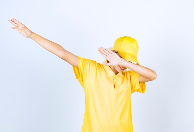 Mujer de entrega en uniforme amarillo de pie y frotando.