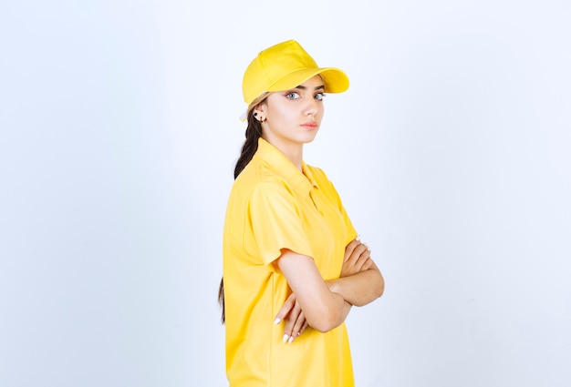Mujer de entrega en uniforme amarillo de pie y mirando a cámara.
