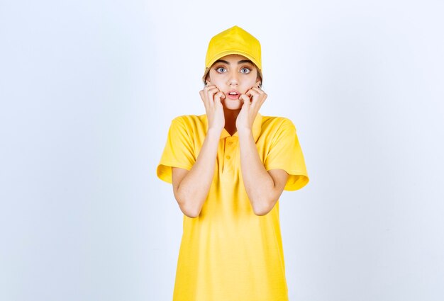 Mujer de entrega en uniforme amarillo de pie y mirando a cámara.