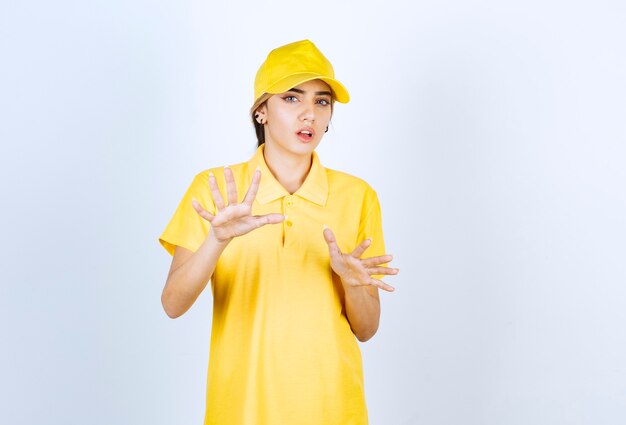 Mujer de entrega en uniforme amarillo de pie y mirando a cámara.