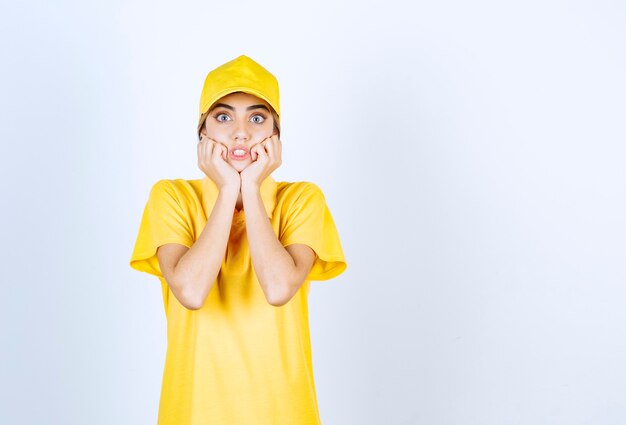 Mujer de entrega en uniforme amarillo de pie y posando.