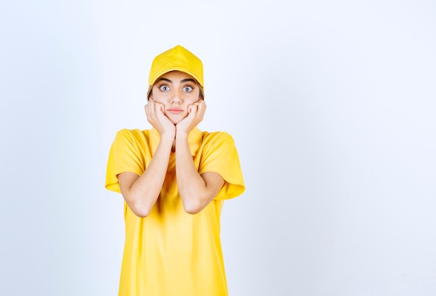 Mujer de entrega en uniforme amarillo de pie y posando.