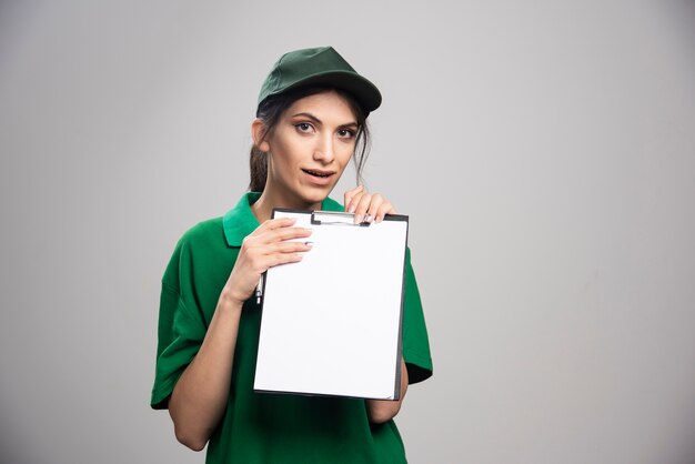 Mujer de entrega en uniforme verde con portapapeles.