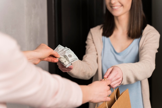 Mujer entregando bolsa de papel y recibiendo billetes