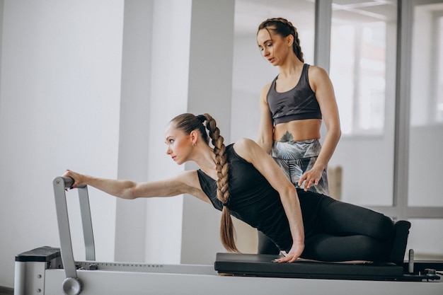 Mujer con entrenador de pilates practicando pilates