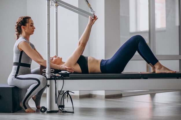 Mujer con entrenador de pilates practicando pilates