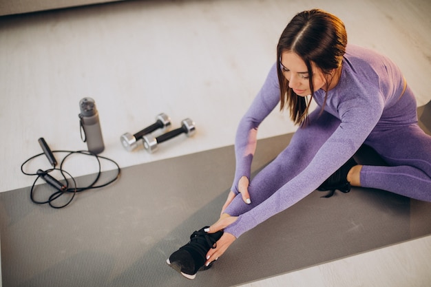 Foto gratuita mujer entrenando en casa sobre colchoneta con mancuernas y comba