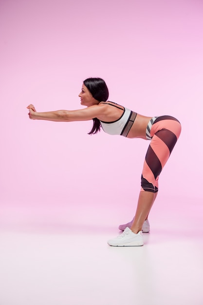 La mujer entrenando contra la pared rosa