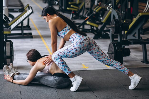 Mujer entrenando en el gimnasio con entrenador de fitness femenino