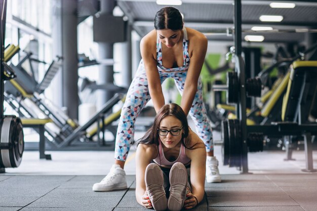 Mujer entrenando en el gimnasio con entrenador de fitness femenino