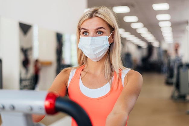Mujer entrenando en el gimnasio con máscara médica
