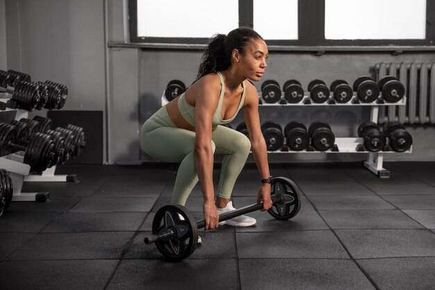 Mujer entrenando para levantamiento de pesas en el gimnasio