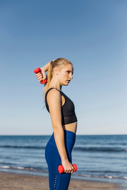 Mujer entrenando con pesas en la playa