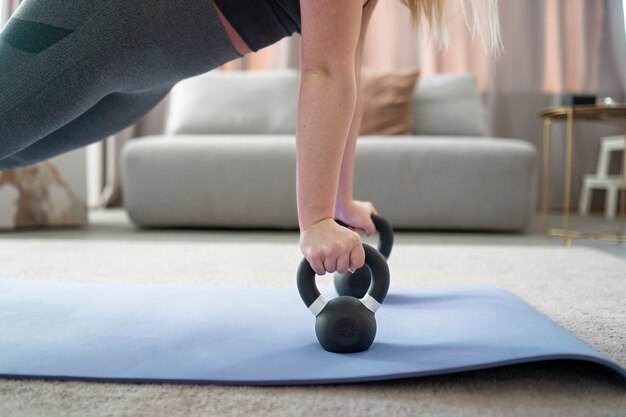 Mujer entrenando con pesas rusas en colchoneta