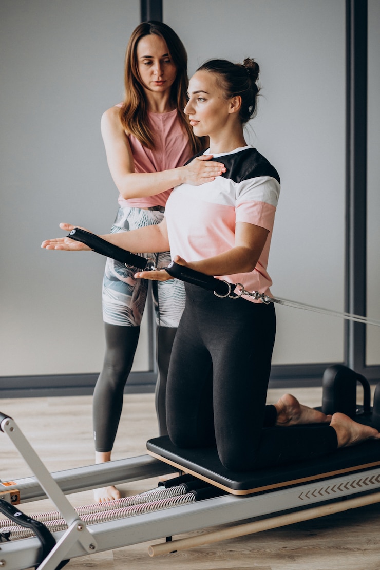 Foto gratuito mujer entrenando a pilates en el reformador