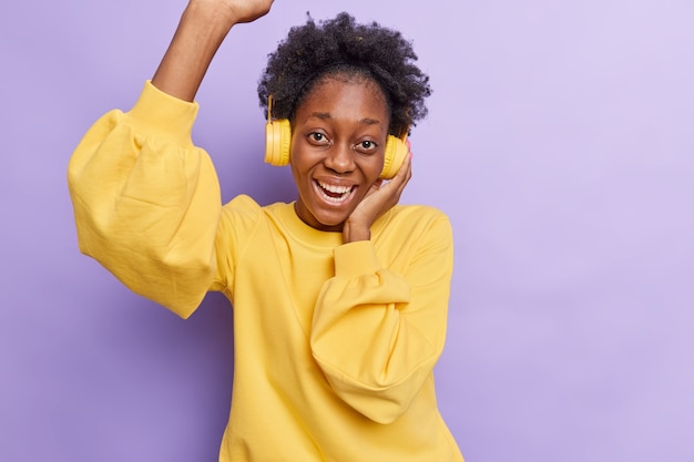 Mujer entretiene en casa durante el covid 19 cuarentena escucha música en auriculares disfruta de su canción favorita aislada en violeta