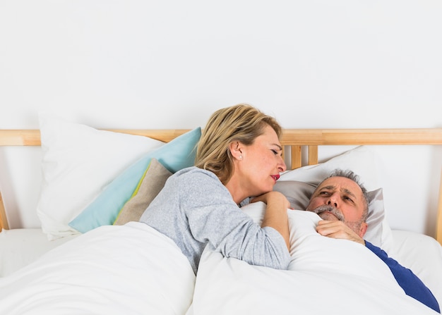 Foto gratuita mujer envejecida tirado cerca de hombre triste en edredón en cama