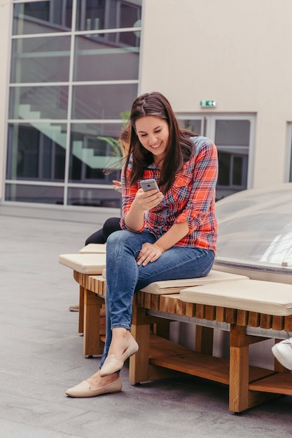 Mujer enviando mensajes de texto por teléfono al aire libre