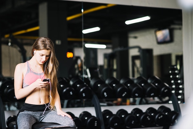 Mujer enviando mensajes de texto por teléfono en el gimnasio