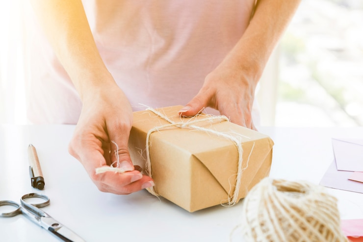 Foto gratuito mujer envolviendo la caja de regalo en mesa