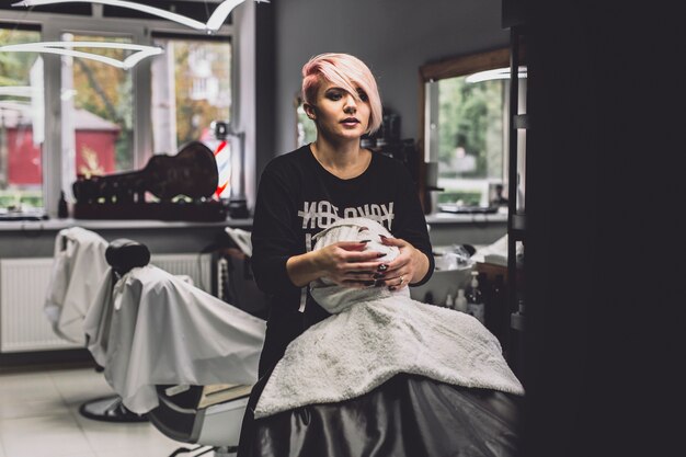 Mujer envolviendo la cara del cliente en peluquería