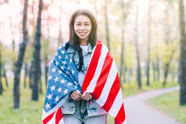 Mujer envuelta en bandera americana al aire libre