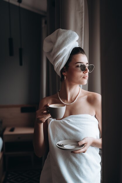 Mujer envuelta en una toalla tomando café