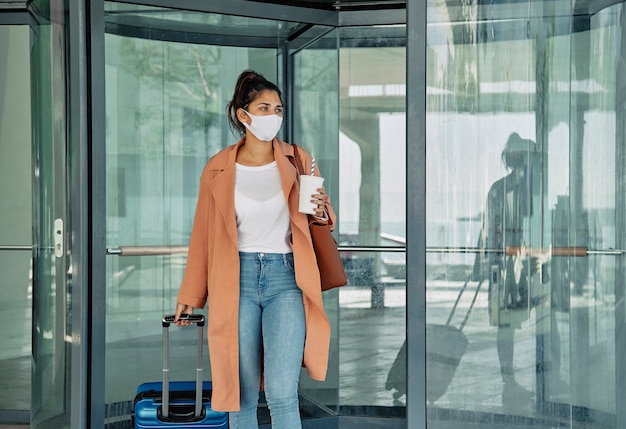 Mujer con equipaje y máscara médica en el aeropuerto durante la pandemia