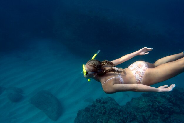 Mujer con equipo de buceo nadando en el océano