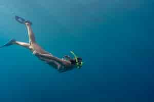 Foto gratuita mujer con equipo de buceo nadando en el océano