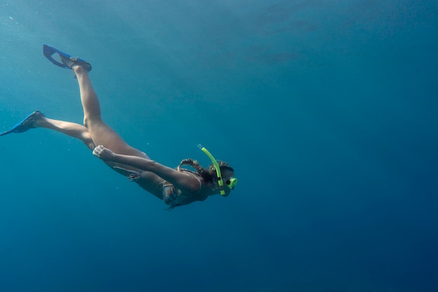 Mujer con equipo de buceo nadando en el océano